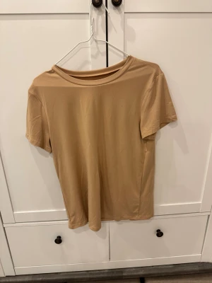 Beige basic t-shirt i bomull - En enkel och stilren beige t-shirt med rund hals och korta ärmar. Perfekt för dig som gillar minimalistisk stil och vill ha en mjuk och skön tröja i garderoben. Materialet känns lätt och bekvämt mot Beige basic t-shirt i bomull.