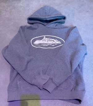 Grå Corteiz Hoodie - Tjena! Säljer nu denna gråa corteiz hoodie då den inte passar mig så bra längre. Tröjan har huva, ribbade muddar och en klassisk känguruficka framtill. Mjuk insida och avslappnad passform. Den har inga defekter förutom att huvan är lite krympt i tvätten. Den passar ungefär S-M skulle jag säga men mer åt S hållet. Skriv om du har några funderingar!