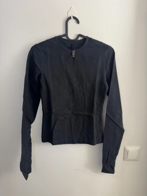 Svart långärmad tröja från SKIMS - ny XS - En stilren svart långärmad tröja från SKIMS i mjuk bomull. Modellen har rund halsringning och en klassisk passform som funkar till många olika looks. Perfekt att matcha med jeans eller kjol för en enkel och snygg outfit.
