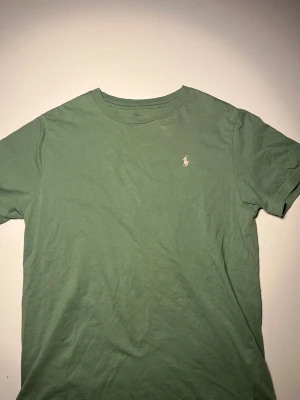 Grön t-shirt från Polo Ralph Lauren - Snygg grön t-shirt från Polo Ralph Lauren med klassisk rund hals och broderad logga på bröstet. Tillverkad i mjuk bomull som känns skön mot huden. Perfekt basic-plagg med stilren look och relaxed fit.