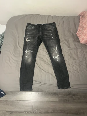 Replay jeans svarta med slitningar - Svarta Replay jeans i modellen 573 Bio med slim fit och snygga slitningar på benen. I nyskick‼️‼️Jeansen har fem fickor, normal slimmad passform, tvär feta och sällsynta. Säljer eftersom att de inte kommit till användning. Pris är inte hugget i sten.🕺