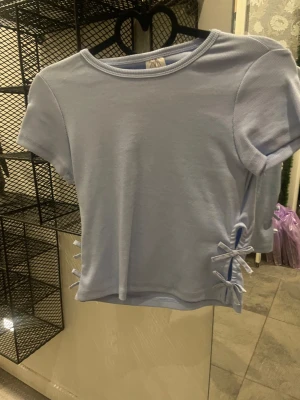 Ljusblå ribbad topp med snörning - Supersöt ljusblå topp med rosetter på sidan. Från  Zara, finns nog ej kvar där på Zaras sida💗💗