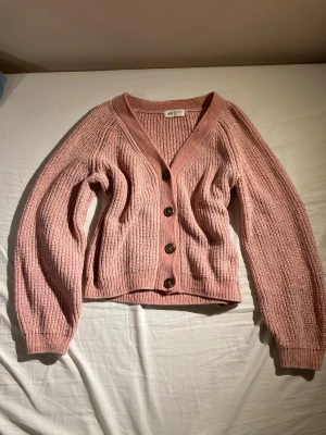 Rosa stickad kofta från HM - Mysig rosa stickad kofta från H&M med grov ribbad struktur och fyra stora knappar framtill. Perfekt att slänga på sig när det är lite kyligt ute. Säljer endast pga att den är för kort då jag är 173.💕