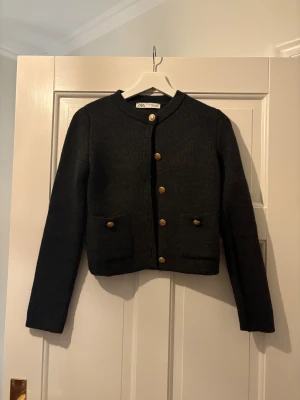 Mörkgrå stickad kofta med guldknappar från Zara - Snygg mörkgrå kofta med jättefina guldknappar från märket Zara i storlek s. Den har två jättefina fickor framtill och är i en lite kortare modell. Den är bara använd en gång så i jättebra skick⭐️Den har en jättefin passform, är i bra material och kvalité. Den är dessutom enkel att styla och passar till allt👍🏻Skriv om funderingar, lämna gärna omdöme om köpt och priset kan diskuteras😊