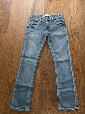 Levi's 511 Slim jeans blå - Säljer ett par Levi's 511 Slim jeans i klassisk blå tvätt. Modellen har smal passform, fem fickor och snygga kontrastsömmar. Jeansen är tillverkade i slitstarkt denim och har en rak siluett som passar till sneakers eller boots. 