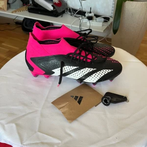 Adidas Predator accuracy.1 SG fotbollsskor - Säljer ett par sprillans nya Adidas Predator accuracy.1 i storlek 43 1/3.  Sulan är SG (skruvdobbar, andvänds för soft ground) ovandelen är av mjukt syntetiskt material med grepp. Till dessa skor så tillkommer det ett justeringsverktyg för dobbarna och ytterligare 4 st dobbar (2 långa och 2 korta) (visas i bild 5). Säljer dessa fotbollsskor då de har blivit för små. Vid frågor och funderingar kring skon eller priset så är det bara att höra av sig. PRISET KAN DISKUTERAS VID SNABB AFFÄR