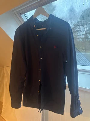 Ralph Lauren Skjorta - Ralph Lauren skjorta i mörblå förg med röd brodering av märket. 