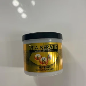 Vita-Keratin Salon Daily Treatment - INTE ÖPPNAD! En burk Vita-Keratin Salon Daily Treatment med svart lock och guldfärgad etikett. Produkten innehåller vitamin E, keratin och arganolja. Perfekt för dig som vill ge håret extra vård och näring. Viral från TikTok 