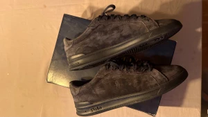 Svarta sneakers från Polo Ralph Lauren - Snygga svarta sneakers från Polo Ralph Lauren i mocka med diskret logga på sidan och Polo-detalj på hälen. Skorna har svart snörning, platt sula och en stilren, låg profil som passar till det mesta. Perfekta för dig som gillar klassisk och clean streetstil.