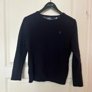 Mörkblå merinoull tröja från Ralph Lauren - Säljer en  mörkblå tröja från Ralph Lauren i merinoull. Storleken är M men sitter som XS då den har krympt i tvätten. Skriv om du har frågor och priser kan nog sänkas via snabb affär. Den har två extremt små hål som man inte tänker på. Utöver det är den i ett gott skick!