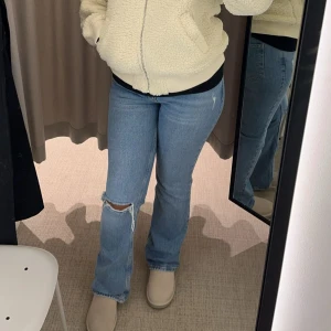 Blå bootcut jeans med slitning - Snygga ljusblå jeans med bootcut passform och slitning vid knät. Pris kan diskuteras
