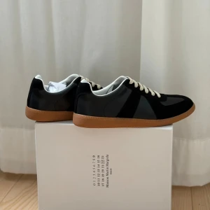 Maison Margiela svarta sneakers - Säljer dessa svarta skor från Maison Margiela. Säljer då de ej passade mig. Skorna är i helt nytt skick aldrig använda och skolådan medföljer. Vid frågor tveka ej om att höra av. Är väldigt flexibel vid förhandling av priset vill bara ej gå i förlust😊