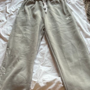 Mjukisbyxor med broderi - Beiga mjukisbyxor från Forum Vondu med broderad logga på benet och bakfickan, samt en vit stjärna på framsidan. Byxorna har snörning i midjan och är tillverkade i mjukt bomullsmaterial. Perfekta för chill dagar och har en loose passform.