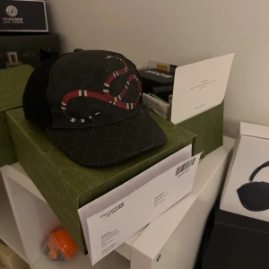 Gucci keps  - Säljer en svart keps från Gucci med klassiskt GG-monogram och en röd-vit orm broderad på framsidan. Kepsen har mesh på baksidan för extra ventilation och justerbar passform. Perfekt för dig som vill sticka ut med en lyxig och trendig accessoar.