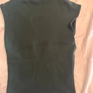 Mörkgrön ärmlös topp från Zara - Snygg mörkgrön topp från Zara i storlek S. Modellen är ärmlös med rund hals och har en clean, enkel design utan mönster eller detaljer. Materialet är mjukt och stretchigt, perfekt för dig som gillar minimalistisk stil.