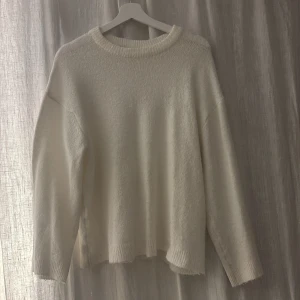 Vit stickad tröja från 157, S - Mysig vit stickad tröja från 157 i storlek S. Tröjan har rund hals, ribbade muddar och en loose passform som ger en chill vibe. Perfekt för lager-på-lager och att matcha med jeans eller kjol. Enkel och clean design utan mönster eller detaljer.