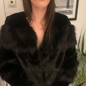 Svart fluffig pälsjacka - Säljer en svart pälsjacka med fluffig och mjuk känsla. Jackan har lång ärm och en snygg, Jackan är helsvart och har en lyxig vibe.