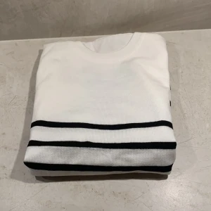 Vit och svart randig stickad tröja - Snygg vit stickad tröja från Verani Clothing med svarta horisontella ränder över hela kroppen och ärmarna. Rund halsringning och ribbade muddar vid hals och nederkant.  Aldrig använd då den inte passade mig. Storleken är S men skulle mer säga att den passar folk med XS. Pris kan diskuteras!😃🚀