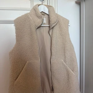 Beige teddyväst från H&M - Mysig beige teddyväst från H&M i storlek S. Köptes för en månad sedan och är endast använd 2 gånger💕Den är krämvit/beige skulle jag säga 