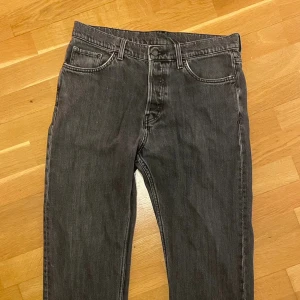 Svarta raka jeans från Weekday - Klassiska svarta Weekday jeans med rak passform och femficksdesign. Jeansen har en mörk tvätt och är tillverkade i slitstarkt denim. Perfekta för dig som gillar en tidlös och avslappnad stil. Helt okej skick