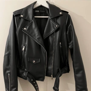 Svart skinnjacka från Zara, M - Skinnjacka från Zara. Den har använts en del men har inga skavanker eller defekter och ser ut som helt ny. Alla dragkedjor går att öppna och stänga så man kan välja själv hur man vill ha på sig den. Säljer den endast då den inte passar mig längre. 