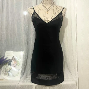 Svart satin klänning från Victoria’s Secret - Supersnygg svart kortklänning i satin med spetsdetaljer vid urringningen och längst ner ger en extra touch. Storlek S, passar strl. 34-36. Dockan är i storlek 36.