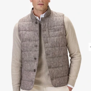 Beige quiltad väst från John Henric - Aldrig använd snygg beige quiltad väst från John Henric med knappar framtill. Perfekt för lager-på-lager under kyligare dagar. Västen har en stilren design med en diskret textur. Skick 10/10