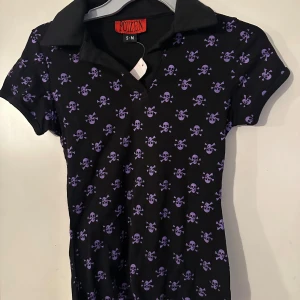 Topp från Poizen storlek S/M - Helt ny topp från Poizen. Storlek S/M. Material i Stretchig bomullstrikå. Lila döskallar.