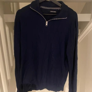 Marinblå half zip tröja Jack & Jones - Snygg marinblå långärmad tröja från Jack & Jones med half zip-dragkedja vid halsen. Tröjan har en enkel och stilren design, perfekt för dig som gillar klassiska plagg. Materialet är mjukt och känns skönt mot huden.