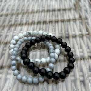 Svart och vit pärlarmband - Två stilrena armband med runda pärlor, ett i svart och ett i vit/grå marmorliknande färg. Perfekt att bära tillsammans eller var för sig för en clean look. Elastisk tråd gör dem enkla att ta på och av.