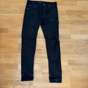 Svarta slim jeans från Nudie Jeans - Säljer ett par klassiska svarta Nudie Jeans i storlek W28 L32. Jeans som funkar både till vardags och fest. Bra skick, inga hål eller större slitage.  ✔️ Slim fit (bekväm passform) ✔️ Färg: Svart ✔️ Nypris ca 1 600 kr  