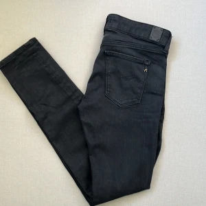 Svarta Replay jeansbyxor skinny fit - Svarta jeans från Replay i modellen Luz med klassisk femficksdesign och snygga detaljer som Replay-logga vid fickan. Jeansen har en skinny passform och är tillverkade i stretchig bomullsdenim för en bekväm känsla. Perfekta för dig som gillar stilrena och moderna jeans.