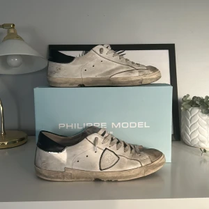 Vita Philippe Model sneakers med svarta detaljer - Säljer dessa feta Phillipe modell skor. Skorna är smutsiga vilket man kan tvätta och göra dom helt nya. Dom har en liten difekt på sulan med ingenting som läcker in. Priset står inte skrivet i sten!!