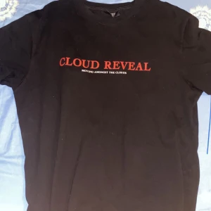 Svart Cloud Reveal t-shirt med tryck - Svart t-shirt från Cloud Reveal med röd text framtill och stort tryck av en örn samt text på ryggen. Klassisk passform och rund hals. Perfekt för dig som gillar streetwear och snygga prints.