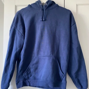 Marinblå hoodie från Bikbok XS - Snygg marinblå hoodie från Bikbok i storlek XS. Tröjan har huva med snörning, stor magficka och ribbade muddar vid ärmslut och nederkant. Perfekt för chill dagar och enkel att matcha med jeans eller leggings.