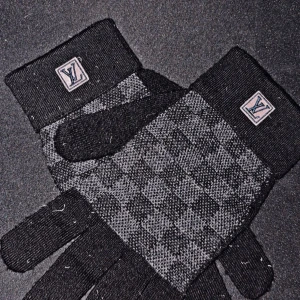 Louis Vuitton handskar - Snygga stickade handskar från Louis Vuitton i svart och grått med klassiskt rutig design. LV-logga på mudden ger en exklusiv touch. Perfekta för att hålla stilen när det är kallt ute.