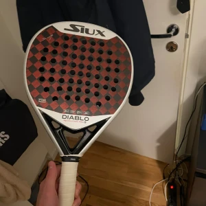 Diablo Revolution Pro 3 - Siux Diablo Revolution Pro 3 padelracket i mycket gott skick. Kolfiberyta med snygg röd/svart design, EM, 15K, DPG, A/5-teknologier. Inga synliga sprickor eller större slitage, endast lätt använd. Perfekt för både avancerade och medelspelare.