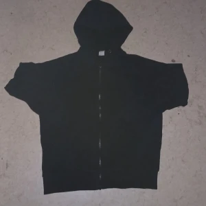 Svart hoodie  - En svart hoodie från Lindex i storlek 158/164. Tröjan har huva, hel dragkedja framtill och är tillverkad i mjukt material. Perfekt för dig som gillar en enkel och clean stil.