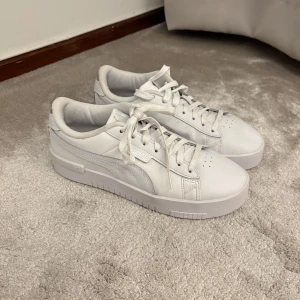 Vita sneakers från Puma med platåsula - Säljer ett par fräscha vita sneakers från Puma med snygg platåsula. Skorna har klassisk snörning, rund tå och är tillverkade i skinn. Perfekta för dig som gillar stilrena och trendiga sneakers med lite extra höjd.