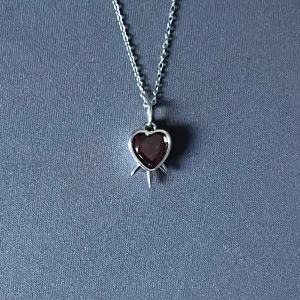 Triple Strike – Red Heart Necklace - Halsband i silverpläterad, rost- och nickelfri rostfri stål med ett 0,9 cm rött hjärta piercat av tre svärd. Justerbar 50 cm kedja, minimalistiskt och iögonfallande.