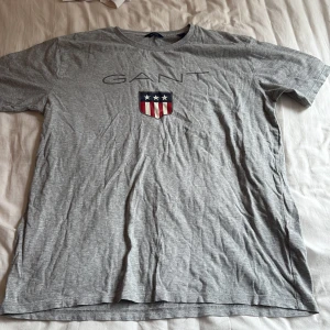 Grå gant T-shirt  - Säljer min gråa gant T-shirt med loggan tryckt över bröstet. Tröjan är i storlek 176 men de motsvarar typ S/M. Säljer för att den inte har kommit till användning 