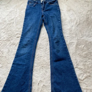 Blå bootcut jeans från g perfect jeans - Snygga blå jeans från gina perfect jeans i bootcut-modell. Klassisk femficksdesign, normalhög midja och utsvängda ben. Jeansen är i ett mjukt denimtyg med orangea sömmar och passar perfekt för dig som gillar retrovibbar.