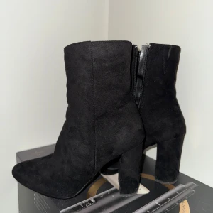 Svarta stövletter från Amisu, strl 36 - Säljer ett par svarta stövletter från Amisu med chunky klack och rund tå. Skorna är i mjuk mockaimitation och har dragkedja på insidan för enkel påtagning. Perfekta för dig som vill ha en stilren och edgy look. Använda endast en gång.