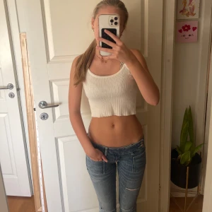 Vit ribbad croppad linnetopp - Säljer en vit croppad linnetopp med ribbad struktur. Toppen är från brandy melville. Materialet känns mjukt och stretchigt, vilket gör den bekväm att bära under varma dagar. 