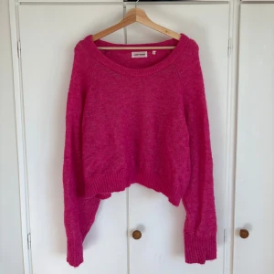 Rosa stickad tröja från Carin Wester - Snygg rosa stickad tröja från Carin Wester i storlek S. Modellen är loose fit med croppad passform och långa ärmar. Mjuk och fluffig känsla, perfekt för att ge din outfit en färgboost. Rund halsringning och ribbade muddar vid ärmslut och nederkant🩷