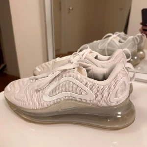 Nike Air Max 720 vita sneakers - Nike Air Max 720 sneakers i helvitt med futuristisk design och genomskinlig maxdämpad sula. Ovandel i mesh och syntet med snygga vågiga detaljer och snörning. Perfekta för dig som gillar sportig och modern stil.