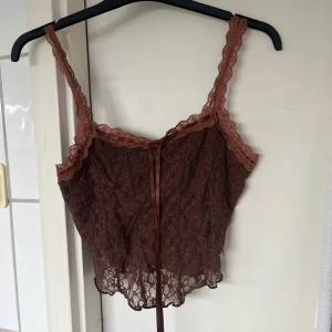 Brun spetsig linnetopp med snörning - Säljer en brun linnetopp i spets. Knappt använd 