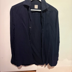 Mörkblå slim skjorta från Stenströms - Snygg mörkblå skjorta från Stenströms i slimline-modell. Skjortan har klassisk krage,  knäppning framtill och långa ärmar. Perfekt för dig som gillar stilrena och enkla plagg med en modern passform.