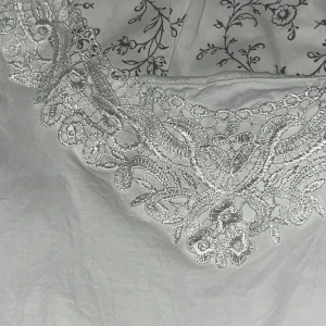 Vit linnetopp med spetsdetalj -  vit linnetopp med tunna axelband och snygg spetsdetalj längs urringningen . Står ingen storlek men tror den är L/M 