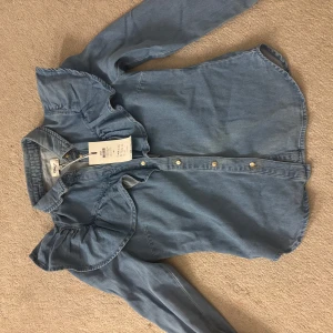 Blå volangskjorta från ONLY - Snygg blå skjorta från ONLY! Prislappen sitter kvar och den är inte använd. Nypris 480kr!